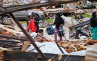 People move through the debris in tornado-hit Mississippi.