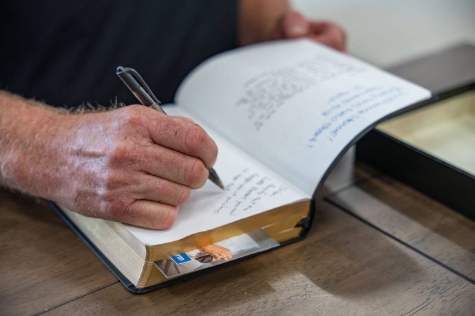 Team member who worked on Brian's home signs the Bible he will receive from Samaritan's Purse