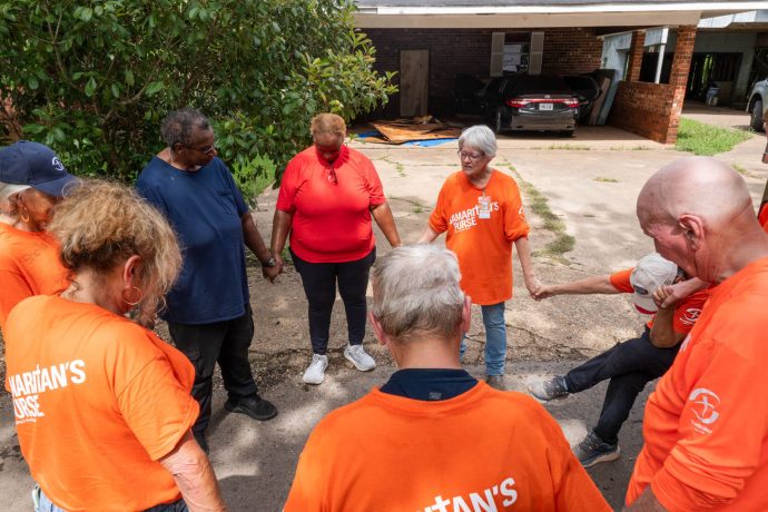 Volunteers circle in prayer with Henrietta and Joyce