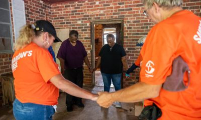 Orange-shirted volunteers pray with Louisiana homeowners