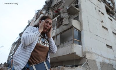 A woman walks past a building damaged during an earthquake in La Guaira, Venezuela, Thursday, June 25, 2026. (AP Photo/Pedro Mattey)