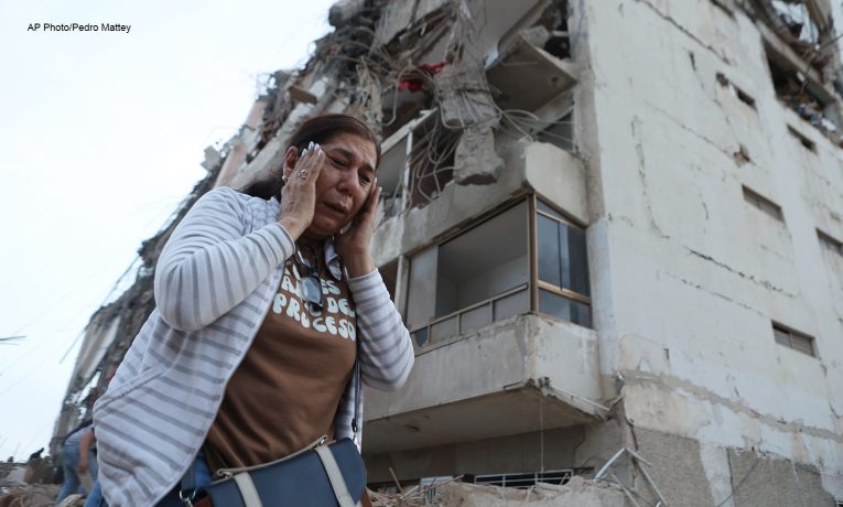 A woman walks past a building damaged during an earthquake in La Guaira, Venezuela, Thursday, June 25, 2026. (AP Photo/Pedro Mattey)