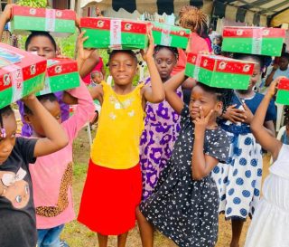 group of girls from Gabon holding shoebox gifts on top of their heads