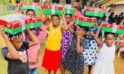 group of girls from Gabon holding shoebox gifts on top of their heads