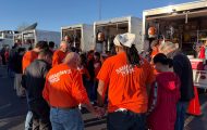 volunteers in orange T-shirts circle to pray in front of Disaster Relief Vehicles