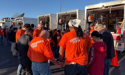 volunteers in orange T-shirts circle to pray in front of Disaster Relief Vehicles