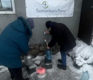 Ukrainians collect water at a church tap