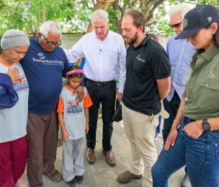 Franklin Graham, joined by daughter, Cissie Graham Lynch and Samaritan's Purse board member Melvin Graham, pray with Pastor Eusebio and his family.