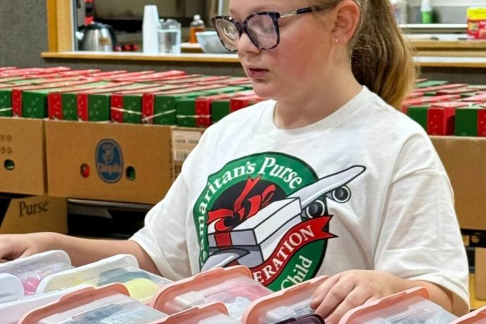 Abigail praying over rows of shoebox gifts