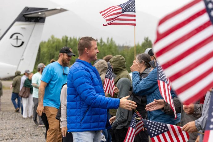 Military couples receive a hero's welcome when they land in Port Alsworth, Alaska, with a line of patriots waving Old Glory as they shake their hands.