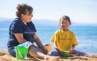 Dara and her grandmother Judi fill buckets with sand at a lakeside