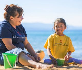 Dara and her grandmother Judi fill buckets with sand at a lakeside