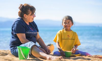 Dara and her grandmother Judi fill buckets with sand at a lakeside