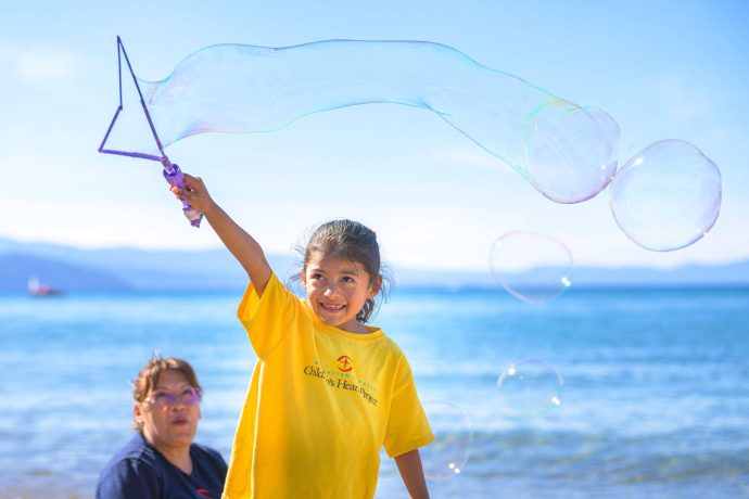 Dara waves a large bubble wand as Judi looks on