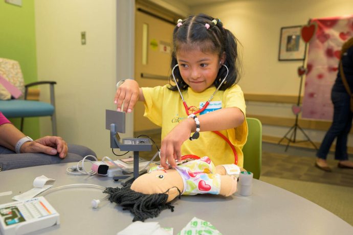 Dara checks the heart beat of a doll at the hospital
