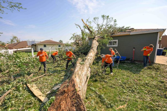 Volunteers work to clean up debris from tree that fell on Mike's house