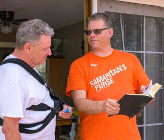 Volunteer presents Bible to homeowner