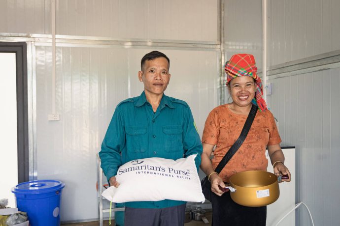 Cham and his wife smile as they display relief items they received from Samaritan's Purse.