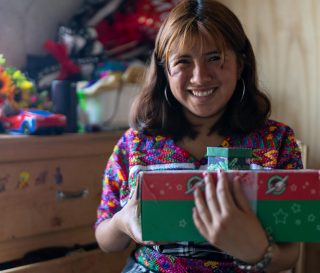 Angelita smiles holding shoebox gift