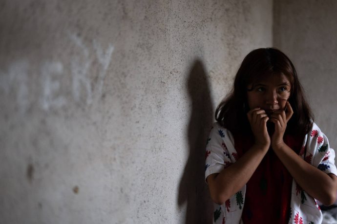 A scared Angelita cowers in a corner