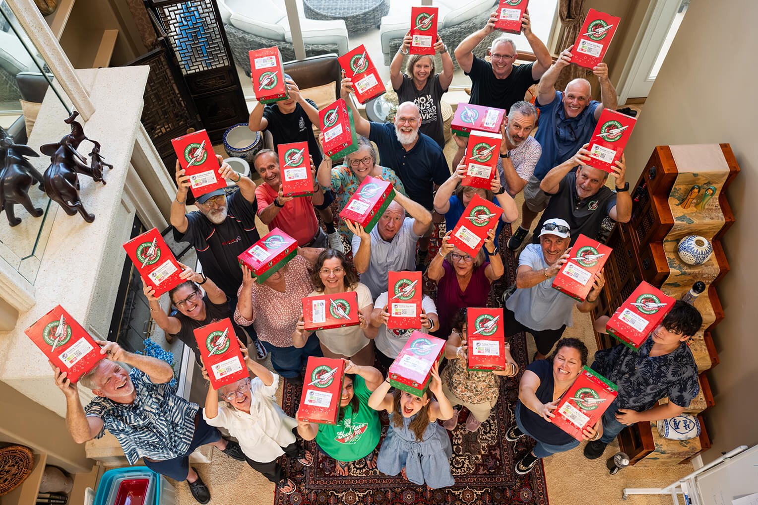 Dozens of young people and parents hold up the Operation Christmas Child shoebox gifts that they packed with Aryana.